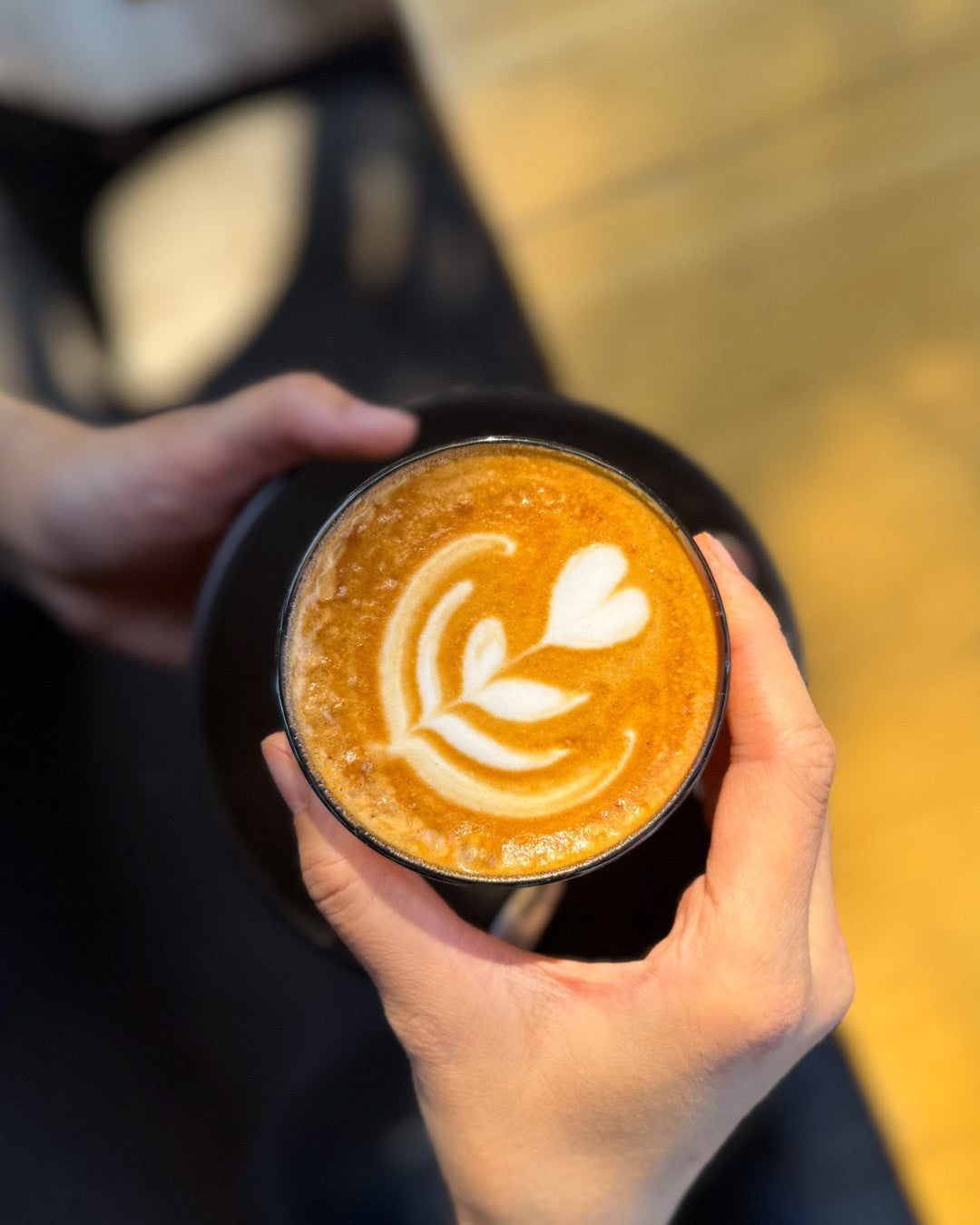 A latte with tulip art held in two hands